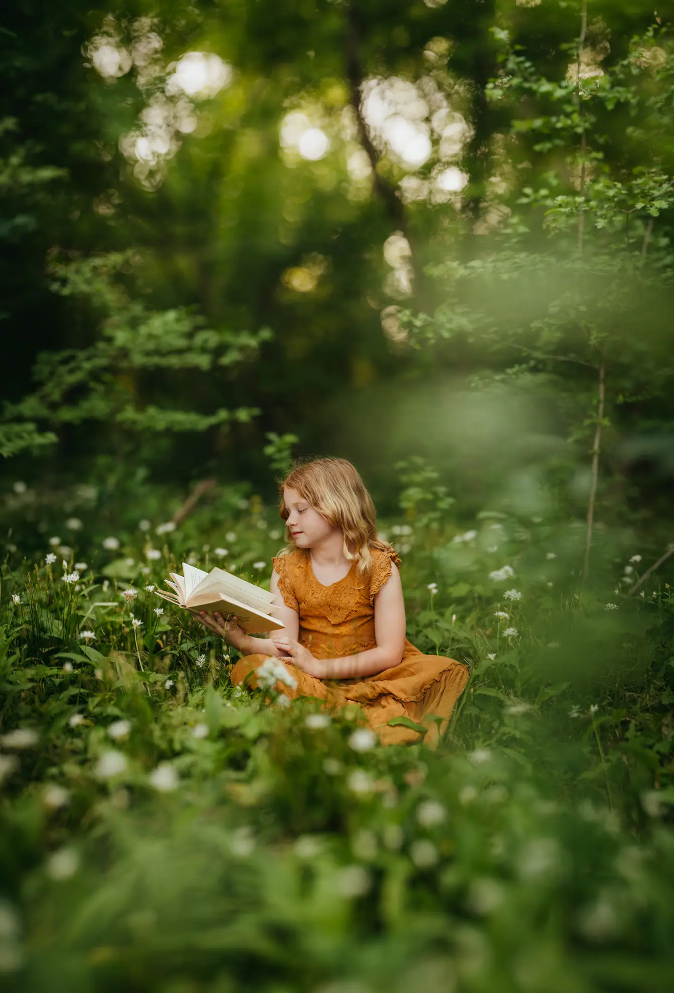 Ein Mädchen sitzt im wald und liest ein Buch, der Hintergrund verschwimmt superweich mit schönem Bokeh